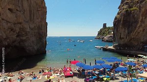 Summer beach crowded people vacation sea travel. Characteristic beach set between two rock ridges, Marina di Praia, Italy, Amalfi Coast. Starting point for many boat trips. People sunbathing, enjoying
