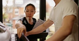 4K Female fitness instructor adjusting treadmill settings for her client at the gym. Slow motion.