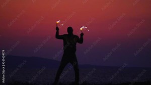 Fire show amazing at night. Fire dancers Swing fire dancing show fire show on the beach dance man in a gold suit juggling with fire. Beautiful fiery rain and sunset at sea. Slow motion video