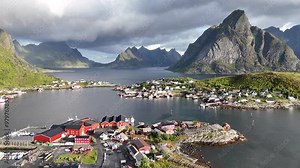 Aerial view of the bridges and towns in Reinefjorden with foggy rainbow background, in Norway - pan, drone shot in 4K. Reine, Reinebringen, Lofoten, Hamnoy.
