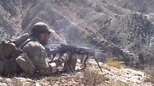 Green Berets Engage ISIS Fighters – Nangarhar Province, Afghanistan U.S. Army Special Forces (Green Berets) provide support by fire from a ridgeline during an engagement in Nangarhar Province. The fight unfolds across rugged terrain with enemy positions spread along the opposite slope. A Mk 48 machine gun delivers sustained fire while a sniper team engages targets at distance. A CCT coordinates close air support, bringing in precision airstrikes that impact enemy positions across the valley, fol