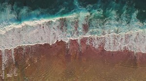Aerial view turquoise green ocean waves crashing on beautiful pink orange sand beach. Scenery beauty of wild nature. Dark water foam waves break wash coastline. Tropic nobody nature seascape. Top down