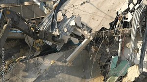 Building demolition. A huge machine arm destroys the house. Dust, debris, bricks, shards fly down. Recorded in slow motion.,