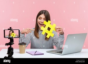Positive woman blogger pointing finger at big yellow hashtag symbol recording video on smartphone camera, telling about tags navigation. Indoor studio Stock Photo - Alamy
