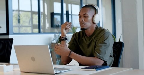 clip-4015624323-african-man-olive-tee-sitting-desk-checking