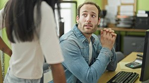 Two workers man and woman using computer speaking at the office