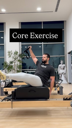 Long box on the reformer. Sit on your sitting bones, facing slightly on a diagonal. Hold the small loop in your hand. As you bring your arm into a “Y” position, extend your legs — they should stay floating the whole time. Keep your neck relaxed and your chest open. Place your opposite hand on the box to help maintain stability. I’m using one blue spring for this Give it a try and let me know how it feels! | Vangelis Dalianis - Pilates Coach, Online Training