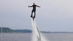 Flyboarding is a new extreme sport where a joyful male flyboarder flies over the water and performs tricks, creating a spectacular display of activity on the water
