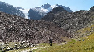 Bearded man walking in the mountains. Hiking alone in the mountains in the summer. A man walks along the crest of a rocky hill high in the mountains. 2x slow motion