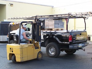 Man Loading Palletized Block On Heavy-Duty Truck Bed Cover On Company Pickup Truck