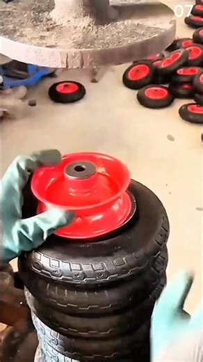 Stacking small rubber tires with red metal rims manually