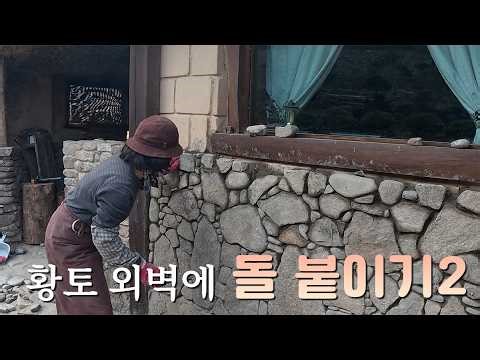 Attaching stones to a red clay exterior wall—stacking and finishing the edges.