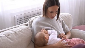 Mother breastfeeding baby girl at home