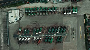 Bird eye aerial view over garbage trucks standing parked at parking lot. These mighty vehicles, with their rugged exteriors and steadfast presence, await their noble mission of waste management.