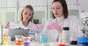 Two scientists conduct a chemical experiment with blue liquid in laboratory