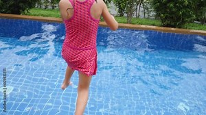 Active little kid girl jump and swim in swimming pool. Have fun at holiday resort. Splash water on summer vacation holiday relaxing