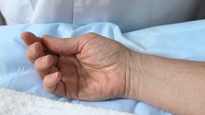 clip-1040017334-doctor-touching-unconscious-patient-hand-after-surgery