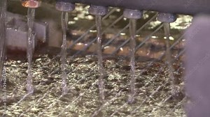 Production of wire by drawing technology. Wires pass through sulfuric acid. Wire production line by drawing method. A thin wire is drawn through a container of liquid.