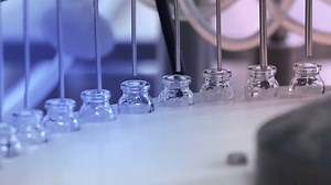 Vaccine filling process in Pharma production machine manufacturing a lot of injections in glass ampoule vial in a pharmaceutical factory making process blue light with latest hi tech machinery