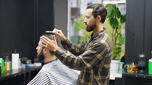 Barber combs and styles hair of male client