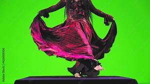 A barefoot gypsy woman without a face with long black hair in a red suit is dancing on a green background. Overall plan