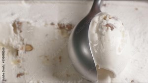 Vanilla ice cream with walnuts. Vanilla Ice cream scooped out from container with a spoon.