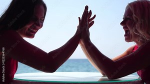 Rock paper scissors being played by two young woman. Close up view female hands playing stone, scissors and paper on sea background, funny carefree game. Friendship, dealing with conflict, having fun.
