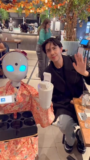 Benji Xavier on Instagram: "Tokyo, Japan is seriously living in the future. The robot café was one of the coolest things I’ve ever seen 🤖✨” About the café The DAWN Robot Café uses avatar robots that are controlled in real time by people with disabilities who can’t easily work outside their homes. Every robot you see taking orders, greeting guests, or bringing drinks is powered by a real person on the other side of the screen. It’s not just a fun experience.. it creates real jobs and real connec