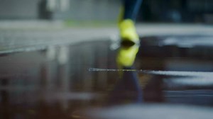Female sports woman jogging outdoors, stepping into puddle. Single runner running in rain, making splash. Slow motion