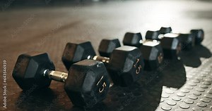 Fitness, background and dumbbells in empty gym for exercise, bodybuilding workout and sports training. Closeup of heavy steel weights, equipment and iron on floor in wellness club for muscle power