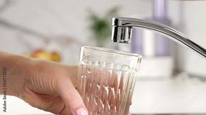 Woman open faucet tap and fill glass with clear water at white kitchen. Closeup