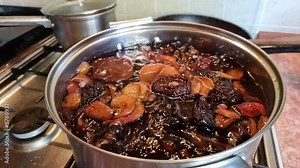Cooking compote from dried pears and apples in a saucepan on a gas stove. The process of bubbling, boiling. Stewed fruit.