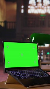 Vertical Professional librarian working on her laptop next to mockup screen in a public library, providing academic resources and guidance. Evaluating educational information within the database. Camera A.