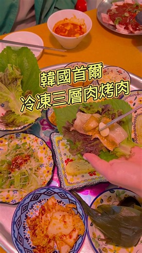 來首爾真的別只吃厚切豬五花！在地人現在都愛這種復古的「冷凍三層肉」。🥩🇰🇷烤到邊緣微焦酥脆，配上吸滿豬油香的烤泡菜和蒜頭，用大片生菜包起來直接「一口塞爆」！蔬菜的清脆完美解膩，重點是價格超便宜喔