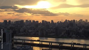 TOKYO, JAPAN : Aerial sunset CITYSCAPE of TOKYO and MOUNT FUJI. View of sun, river and buildings at downtown area. Japanese urban metropolis and nature concept. Time lapse zoom in shot dusk to night.