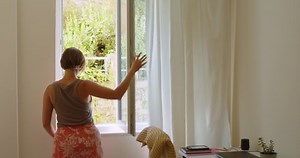 Back view of woman going to the window opening it and looking out