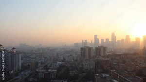 Guangzhou. Time lapse of dawn. There are small and tall houses. There are cars on the road below. The houses in the background are hidden in the fog.