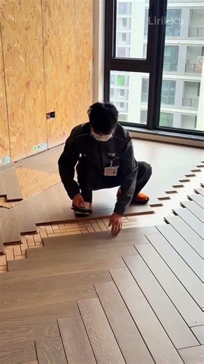 installing a wooden parquet floor in a herringbone pattern using a hammer and small wooden blocks
