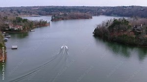 Tracking and Rising Aerial of Boat Cruising on Lake Lanier Georgia US, Smooth Water, Boat Wake, Following Behind Boat with Landscape of Homes and Trees in the Background
