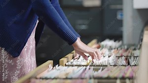 Close-up hand of businesswoman searching for financial and accounting file paperwork in an office file cabinet