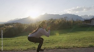 Beautiful young woman squats workout. Beautiful fitness model butt workout outdoors. Sunset with mountains view in background.