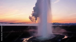 The breathtaking sight of a geyser bursting to life backdropped by the vibrant colors of the dawn sky.