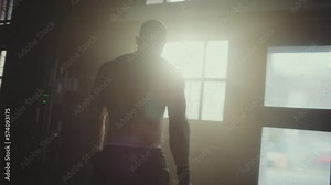 Back view of a shirtless muscular bodybuilder walking to the gym and posing to the camera. Man showing his body on camera