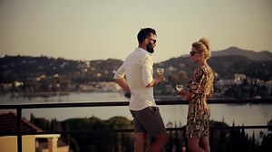 Couple Celebrating Perfect Vacation. All Inclusive Greek Hotel. Greek Island Resort. Honeymoon Drinking Champagne On Resort. Lovers Celebrating Holidays Drinking White Wine. Romantic Enjoying Sunset