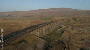 Aerial Drone Shot Pulling away from Ribblehead Viaduct Train Bridge at Stunning Sunrise in Summer in Yorkshire Dales England UK with 3 peaks Whernside mountain in background