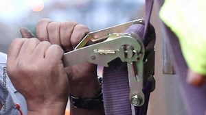 Attaching cargo with strap. Worker securing cargo transportation with strap6