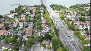A scenic view of the Whitestone Bridge crossing the East River, connecting urban and natural landscapes. The nearby park offers green spaces with river views, with the horizon and the bustling city of