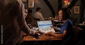 4k, Two businesswoman going over financial statements on a laptop at a restaurant. Slow motion.