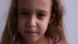 Download Childish laughing baby close-up portrait. A beautiful little girl smiles at the camera. Video. for free