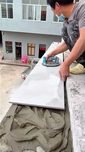 Installing large light grey floor tiles on the adhesive with a suction cup for balcony renovation